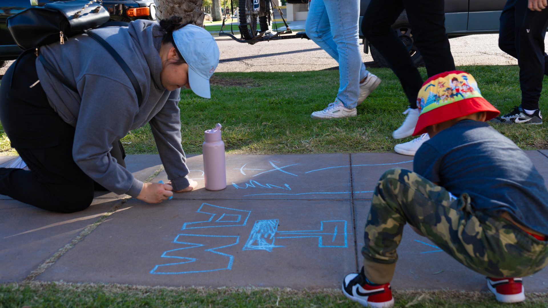 A family drawing sidewalk chalk art together